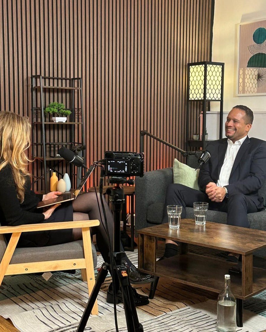 Louis Stedman-Bryce being interviewed on camera in a studio, seated opposite an interviewer