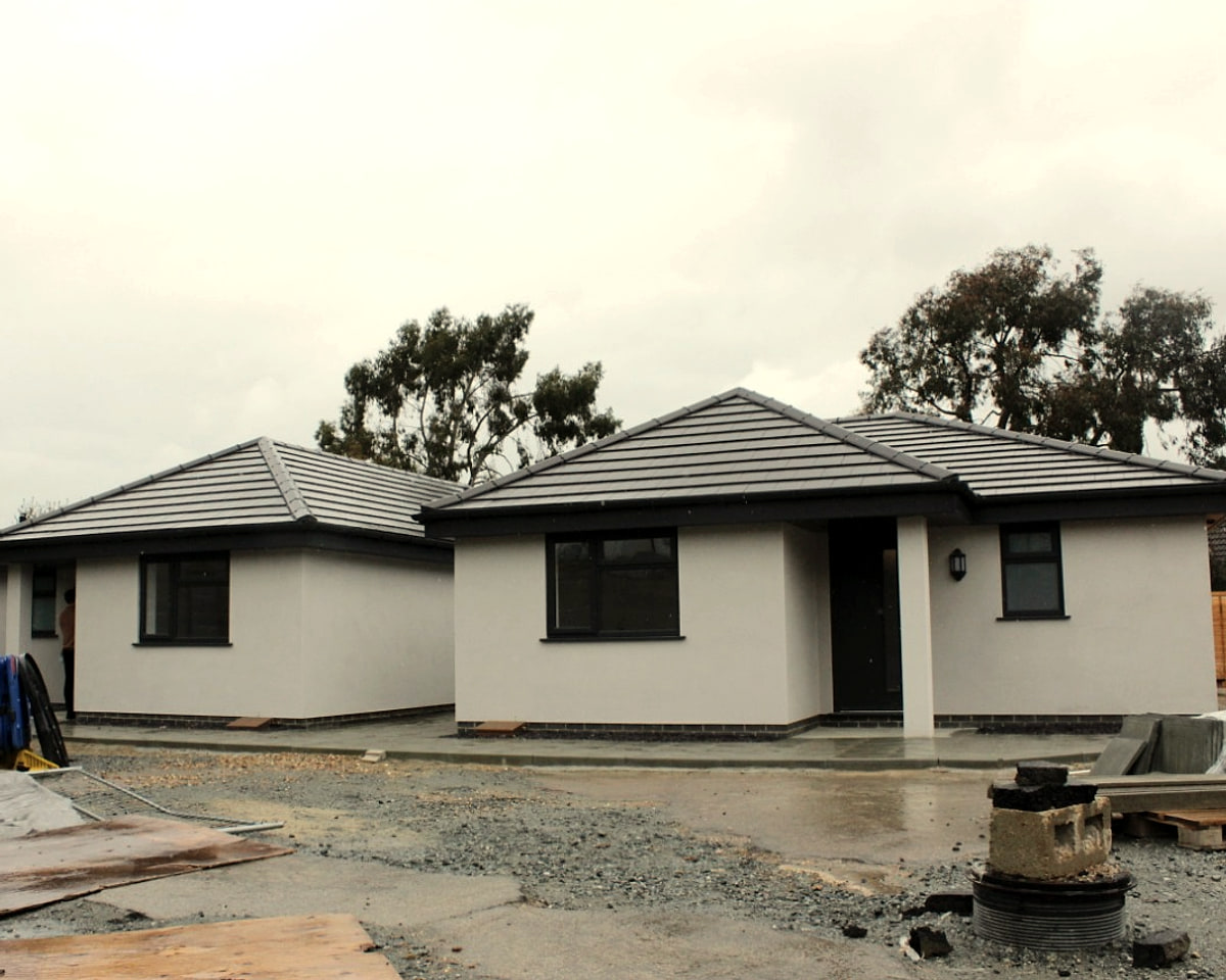 Two newly built single-storey homes on a development site, before landscaping.